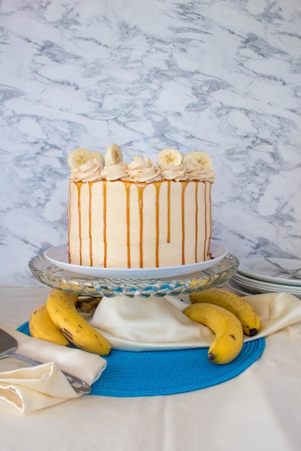 Moist and fluffy Banana cake, filled and frosted with creamy caramel buttercream, and topped with delicious homemade caramel sauce and sliced bananas. This Banana Caramel Layer Cake is the perfect dessert for birthdays, dinner parties, or any occasion!