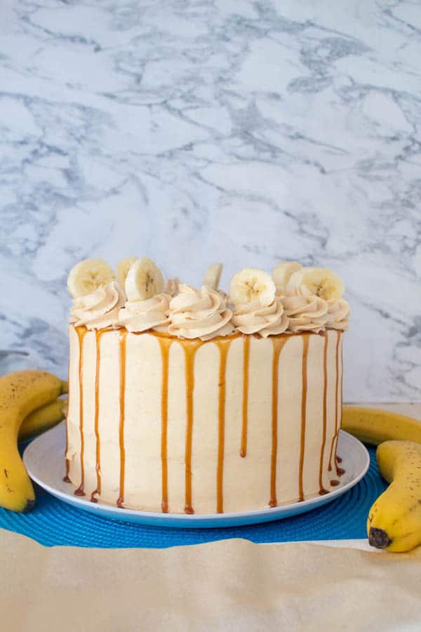 Moist and fluffy Banana cake, filled and frosted with creamy caramel buttercream, and topped with delicious homemade caramel sauce and sliced bananas. This Banana Caramel Layer Cake is the perfect dessert for birthdays, dinner parties, or any occasion!