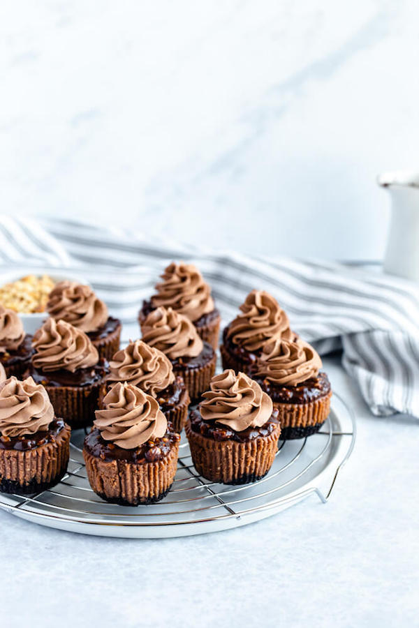 mini nutella cheesecakes stuffed with Ferrero rochers and topped with nutella hazelnut ganache, chocolate whipped cream and chopped hazelnuts 