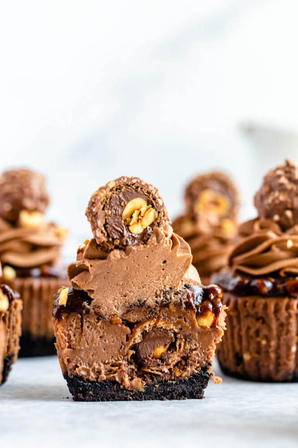 mini nutella cheesecakes stuffed with Ferrero rochers and topped with nutella hazelnut ganache, chocolate whipped cream and chopped hazelnuts 