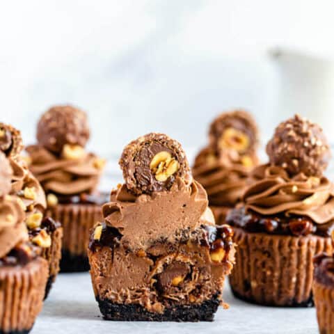 mini nutella cheesecakes stuffed with Ferrero rochers and topped with nutella hazelnut ganache, chocolate whipped cream and chopped hazelnuts