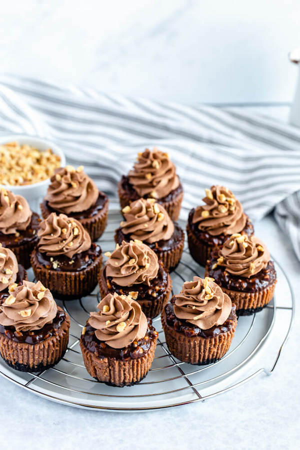 mini nutella cheesecakes stuffed with Ferrero rochers and topped with nutella hazelnut ganache, chocolate whipped cream and chopped hazelnuts 