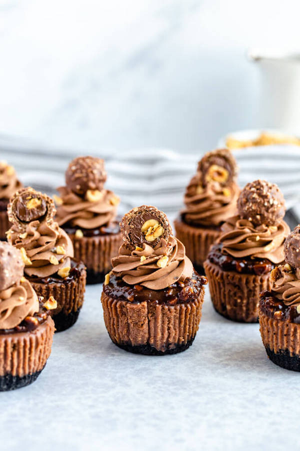 mini nutella cheesecakes stuffed with Ferrero rochers and topped with nutella hazelnut ganache, chocolate whipped cream and chopped hazelnuts 