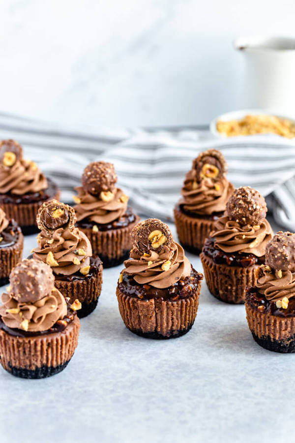 mini nutella cheesecakes stuffed with Ferrero rochers and topped with nutella hazelnut ganache, chocolate whipped cream and chopped hazelnuts 