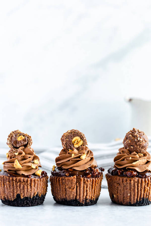 mini nutella cheesecakes stuffed with Ferrero rochers and topped with nutella hazelnut ganache, chocolate whipped cream and chopped hazelnuts 