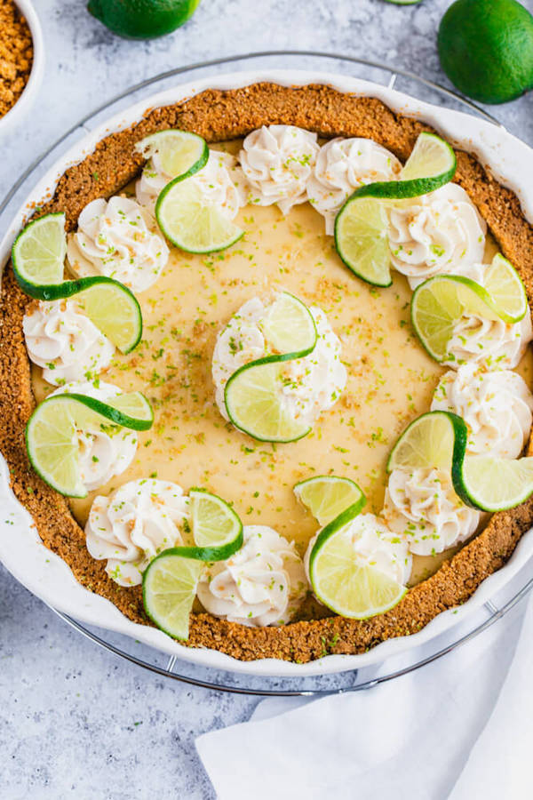 this key lime pie is made with a lime flavoured graham cracker crust, key lime pie filling and decorated with whipped cream, graham cracker crumbs, lime zest and lime twists