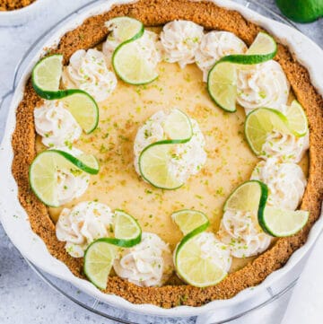 this key lime pie is made with a lime flavoured graham cracker crust, key lime pie filling and decorated with whipped cream, graham cracker crumbs, lime zest and lime twists