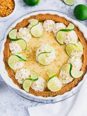 this key lime pie is made with a lime flavoured graham cracker crust, key lime pie filling and decorated with whipped cream, graham cracker crumbs, lime zest and lime twists