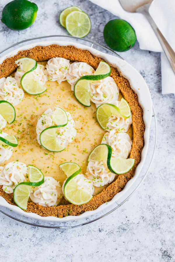 this key lime pie is made with a lime flavoured graham cracker crust, key lime pie filling and decorated with whipped cream, graham cracker crumbs, lime zest and lime twists