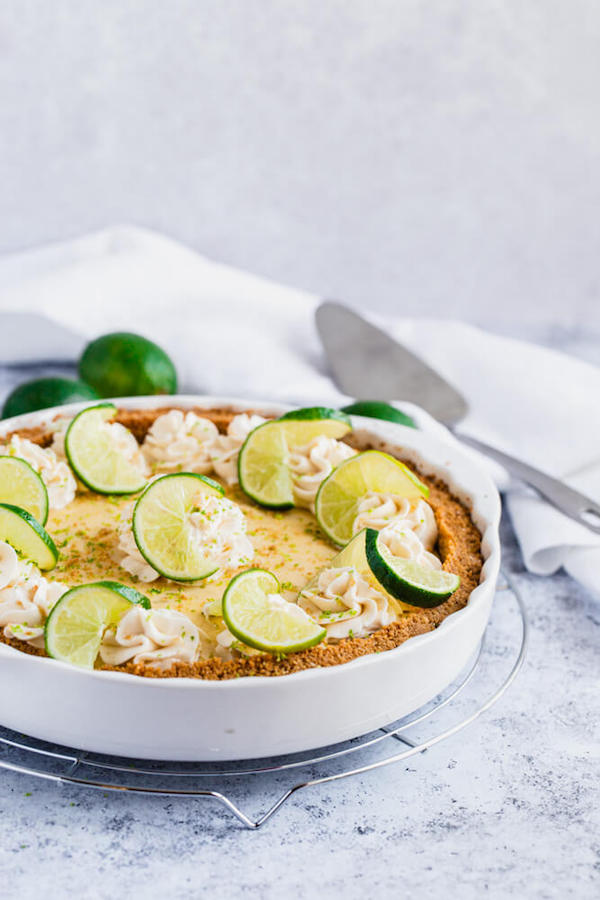 this key lime pie is made with a lime flavoured graham cracker crust, key lime pie filling and decorated with whipped cream, graham cracker crumbs, lime zest and lime twists