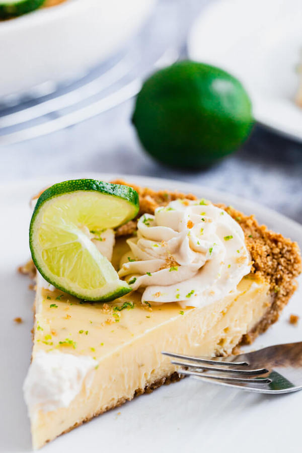 this key lime pie is made with a lime flavoured graham cracker crust, key lime pie filling and decorated with whipped cream, graham cracker crumbs, lime zest and lime twists