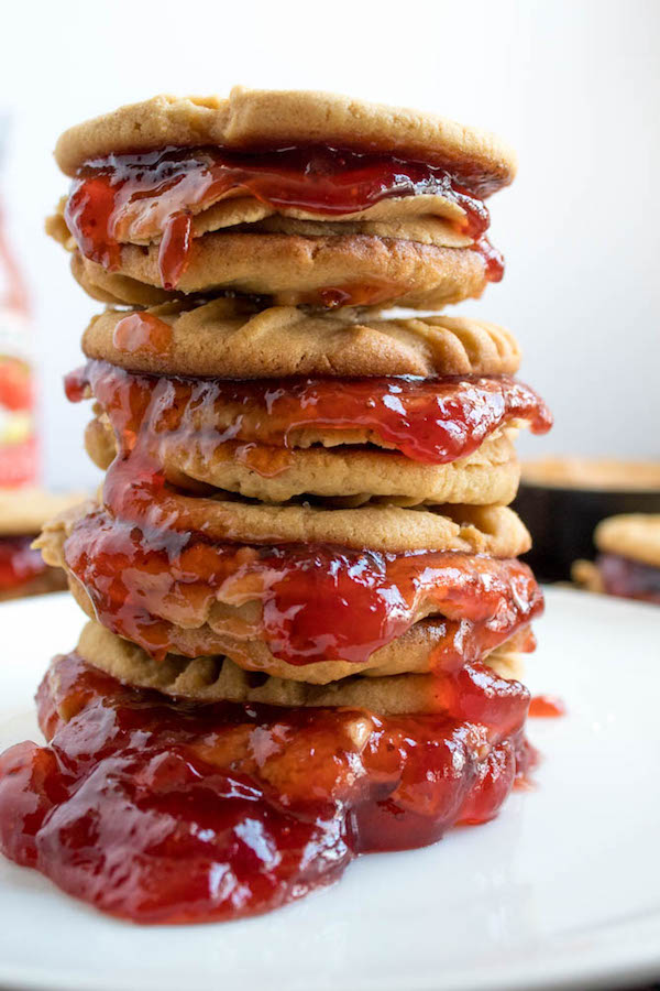 Soft and chewy peanut butter cookies filled with peanut butter frosting and strawberry jam. These Peanut Butter and Jelly Cookie Sandwiches are a sweet and amazing twist to the classic childhood favourite!