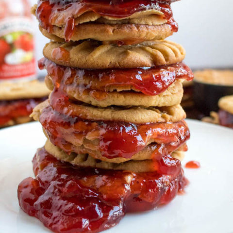 Soft and chewy peanut butter cookies filled with peanut butter frosting and strawberry jam. These Peanut Butter and Jelly Cookie Sandwiches are a sweet and amazing twist to the classic childhood favourite!