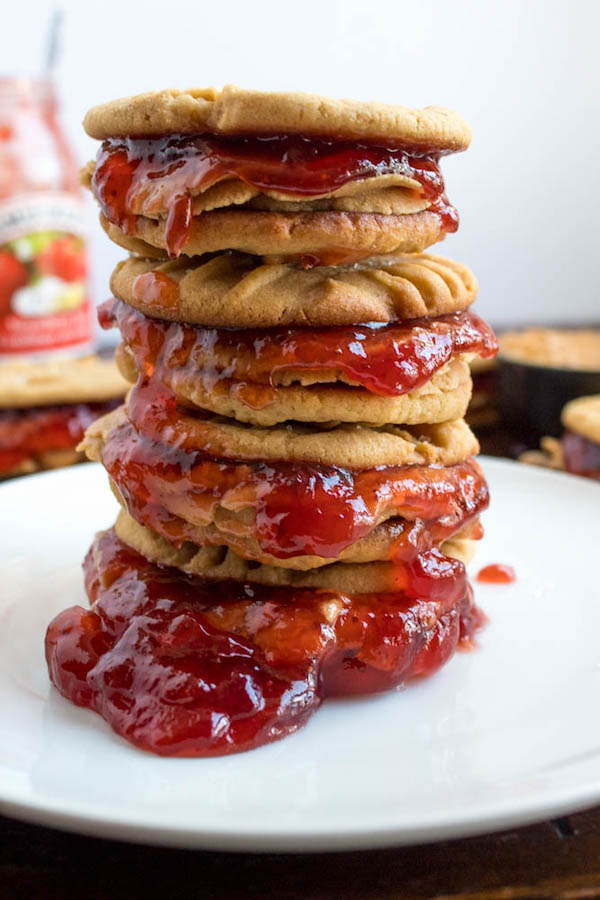 Soft and chewy peanut butter cookies filled with peanut butter frosting and strawberry jam. These Peanut Butter and Jelly Cookie Sandwiches are a sweet and amazing twist to the classic childhood favourite!