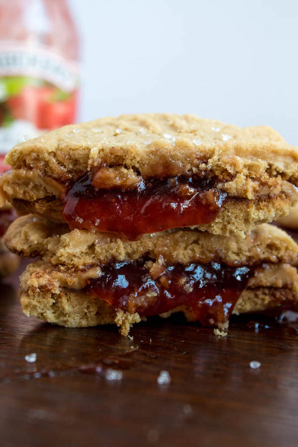 Soft and chewy peanut butter cookies filled with peanut butter frosting and strawberry jam. These Peanut Butter and Jelly Cookie Sandwiches are a sweet and amazing twist to the classic childhood favourite!