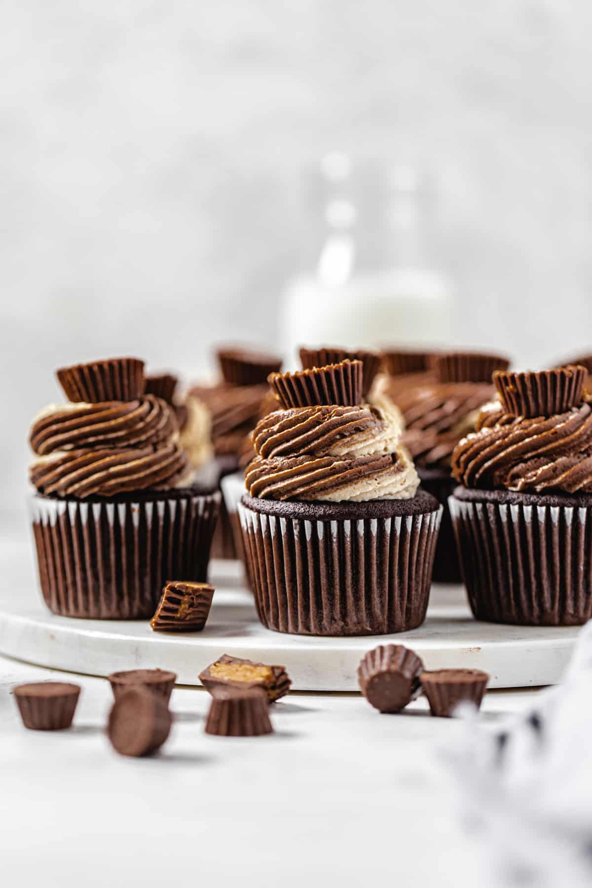 cupcakes on a round marble board with mini Reese's in front and a milk bottle in the background