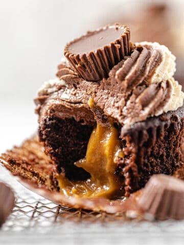 close up of cupcake with a bite taken out of it and peanut butter ganache flowing out