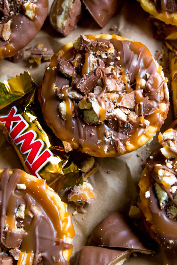 These Mini Twix Tarts taste just like a Twix bar! Mini pre-baked tart shells filled with homemade caramel sauce and topped with milk chocolate and chopped Twix bars. If you love Twix candy bars then this is the perfect treat for you!