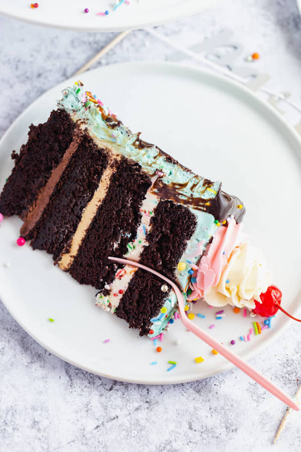 chocolate cake filled with vanilla sprinkle, caramel and chocolate buttercream and covered in a teal sprinkle frosting, topped with maraschino cherries and decorated with more sprinkles.