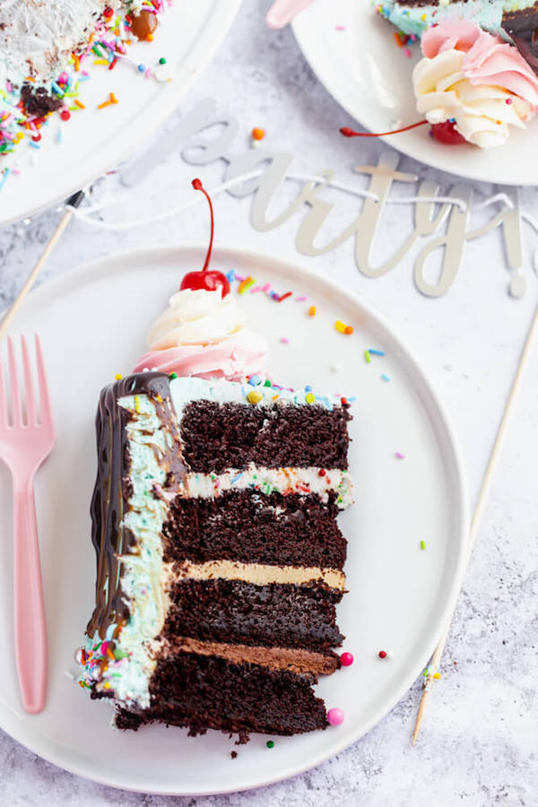 chocolate cake filled with vanilla sprinkle, caramel and chocolate buttercream and covered in a teal sprinkle frosting, topped with maraschino cherries and decorated with more sprinkles.