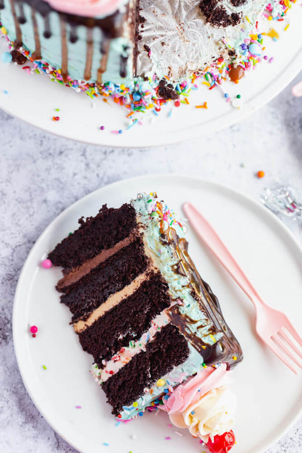 chocolate cake filled with vanilla sprinkle, caramel and chocolate buttercream and covered in a teal sprinkle frosting, topped with maraschino cherries and decorated with more sprinkles.