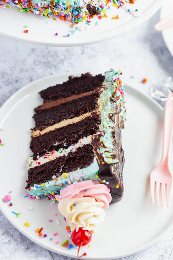 chocolate cake filled with vanilla sprinkle, caramel and chocolate buttercream and covered in a teal sprinkle frosting, topped with maraschino cherries and decorated with more sprinkles.