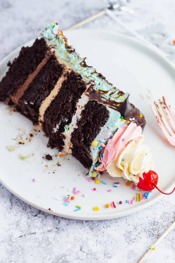 chocolate cake filled with vanilla sprinkle, caramel and chocolate buttercream and covered in a teal sprinkle frosting, topped with maraschino cherries and decorated with more sprinkles.