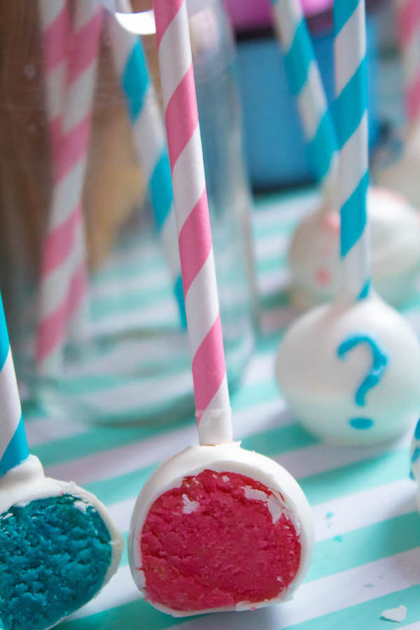 These Gender Reveal Cake Pops are a fun and cute way to surprise your baby shower guests! Once they bite into it, the pink or blue cake inside will reveal if it's a boy or girl!