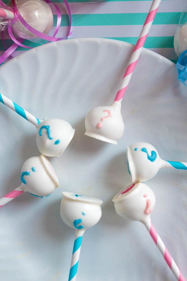 These Gender Reveal Cake Pops are a fun and cute way to surprise your baby shower guests! Once they bite into it, the pink or blue cake inside will reveal if it's a boy or girl!