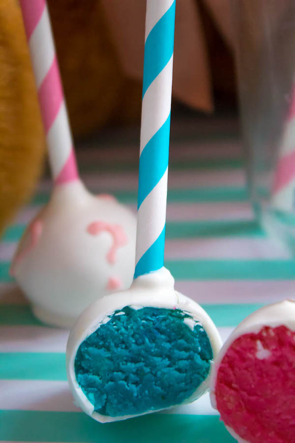 These Gender Reveal Cake Pops are a fun and cute way to surprise your baby shower guests! Once they bite into it, the pink or blue cake inside will reveal if it's a boy or girl!