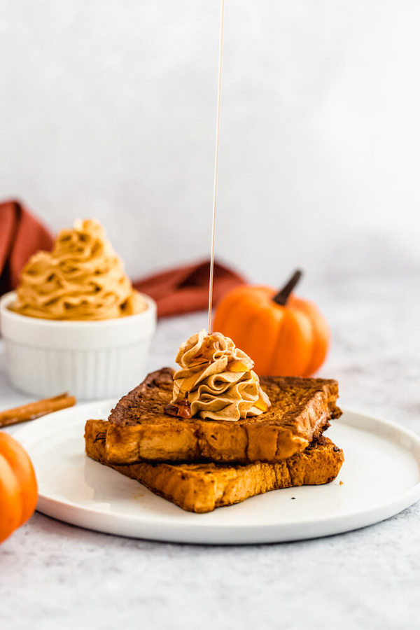 pumpkin French toast topped with icing sugar, maple syrup and whipped pumpkin spice honey butter