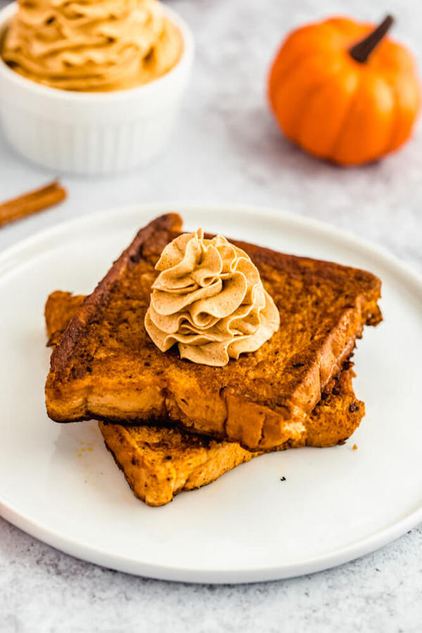 pumpkin French toast topped with icing sugar, maple syrup and whipped pumpkin spice honey butter