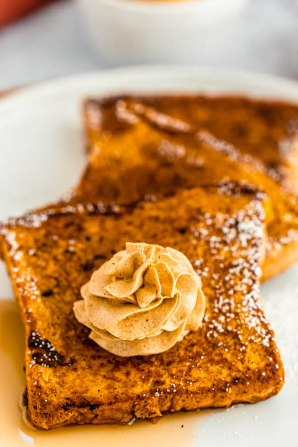 pumpkin French toast topped with icing sugar, maple syrup and whipped pumpkin spice honey butter