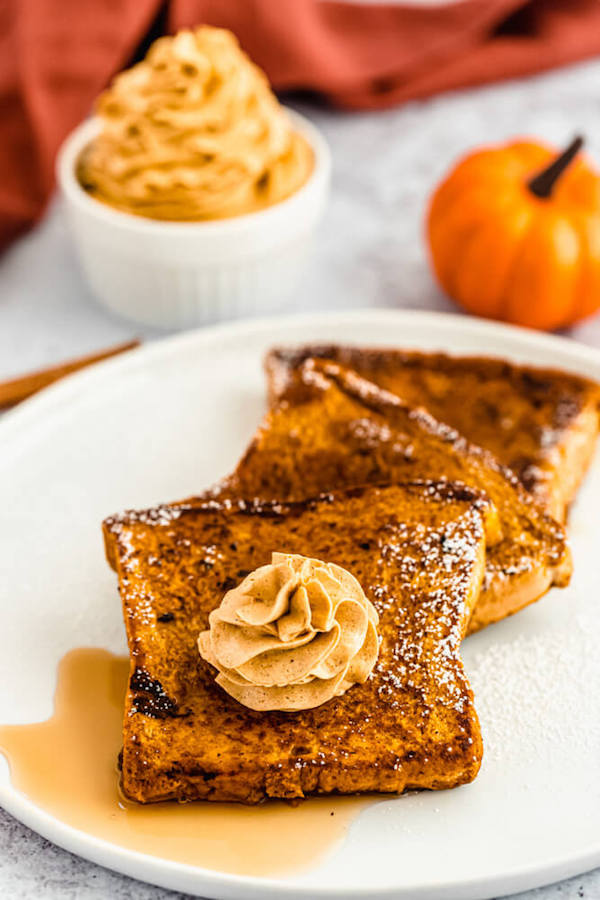 pumpkin French toast topped with icing sugar, maple syrup and whipped pumpkin spice honey butter