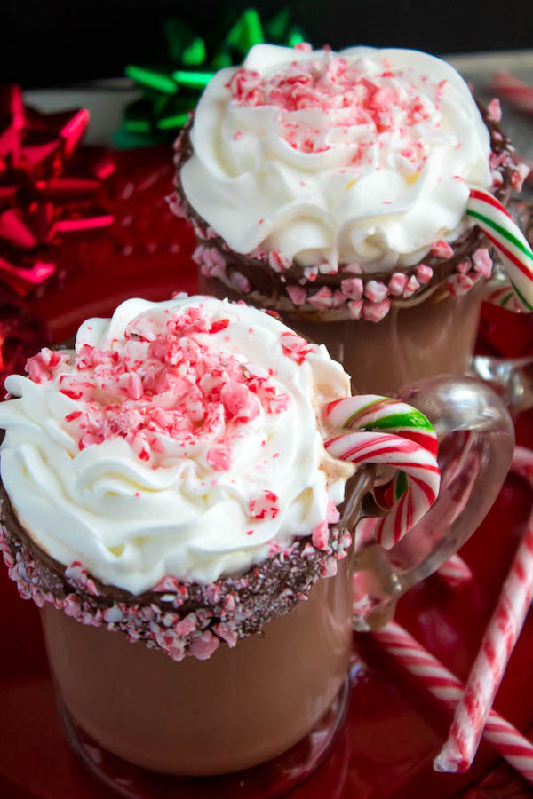 This Candy Cane Hot Chocolate is a warm and cozy Holiday drink perfect for warming up to the cold weather. With a candy cane lined rim, peppermint hot chocolate filled with crushed candy canes, and a peppermint whipped cream topping, this drink screams Christmas! 