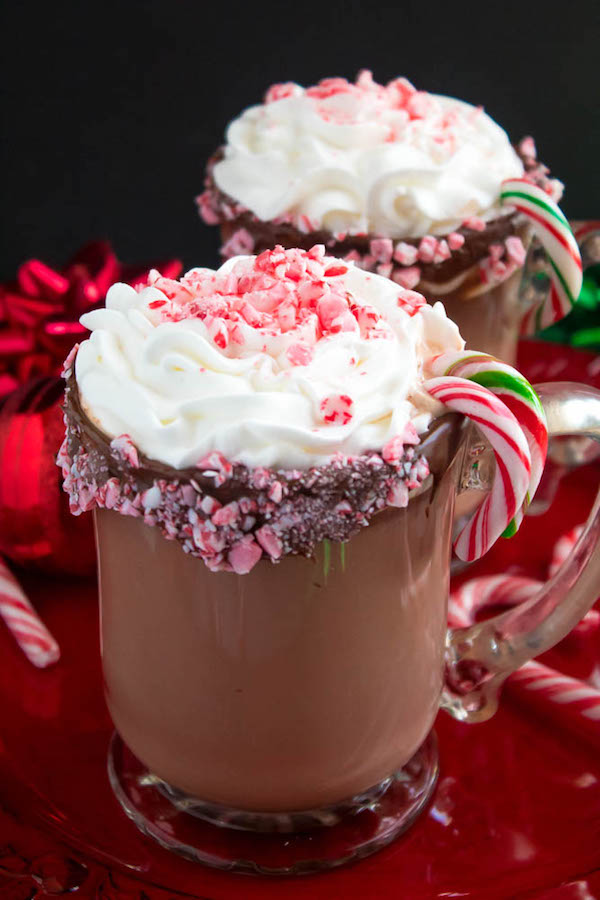 This Candy Cane Hot Chocolate is a warm and cozy Holiday drink perfect for warming up to the cold weather. With a candy cane lined rim, peppermint hot chocolate filled with crushed candy canes, and a peppermint whipped cream topping, this drink screams Christmas! 