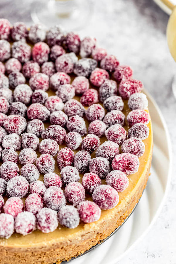 close up of eggnog cheesecake topped with sugared cranberries