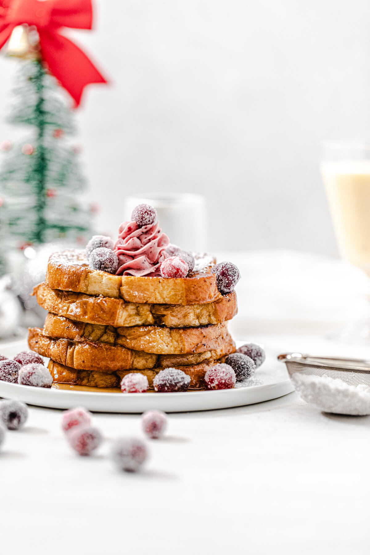 stack of French toast topped with sugared cranberries on a white plate