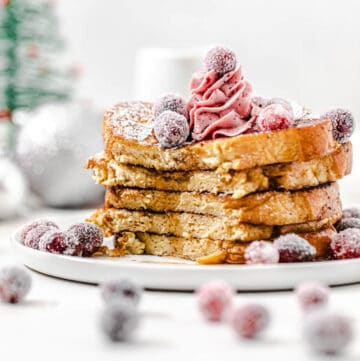 stack of French toast topped with cranberries with the front half sliced off