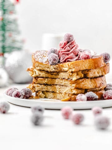 stack of French toast topped with cranberries with the front half sliced off