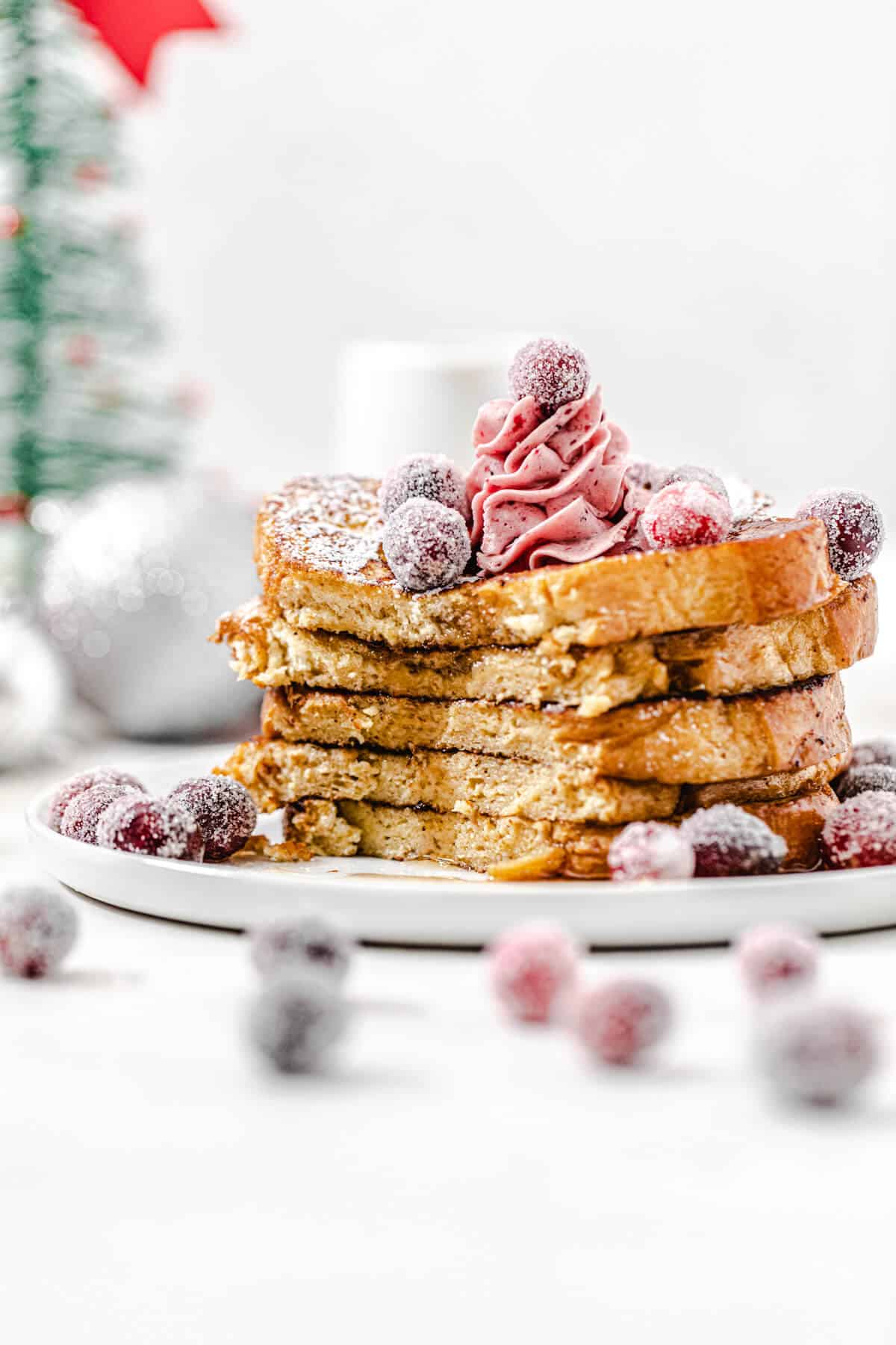 stack of French toast topped with cranberries with the front half sliced off