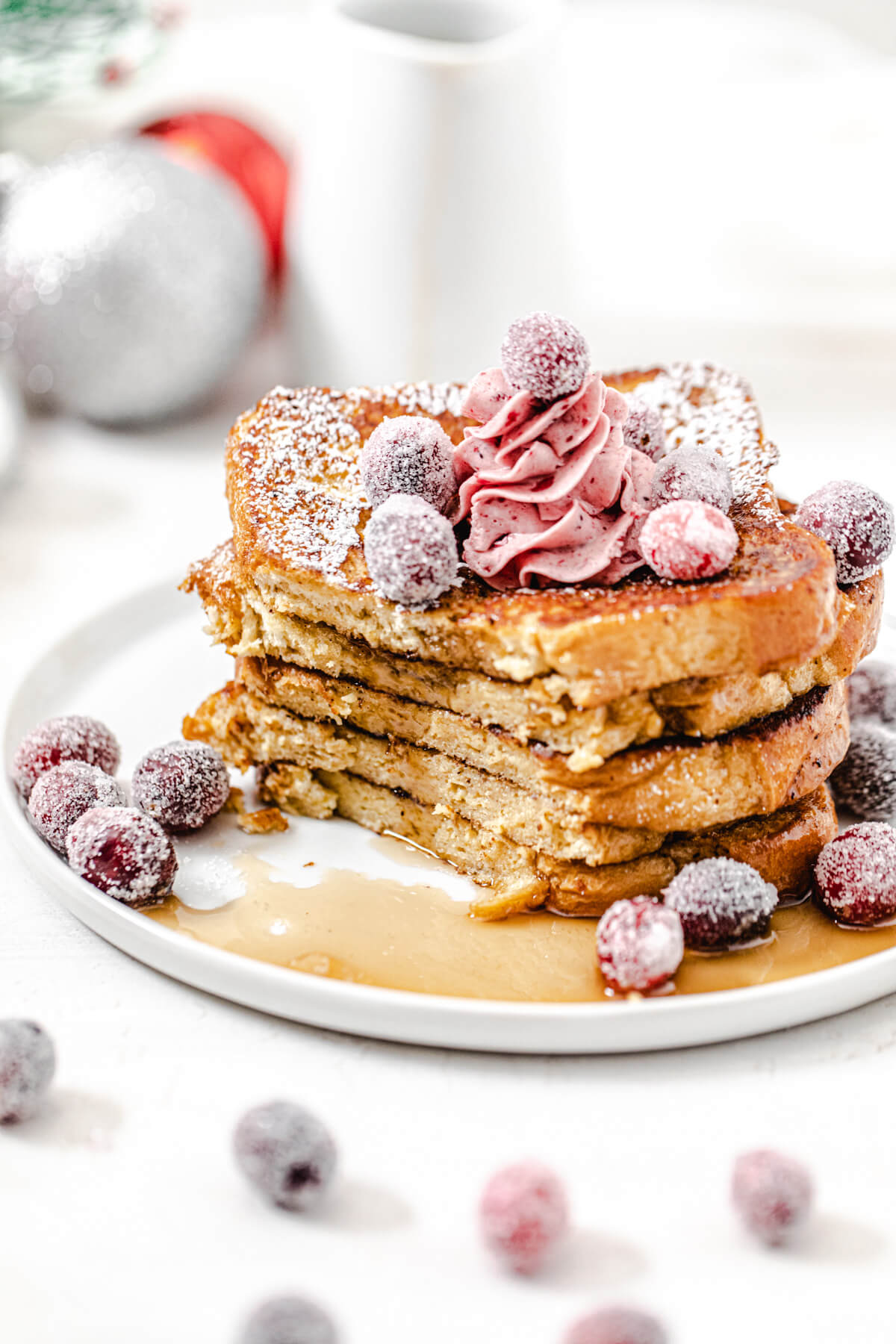 half eaten stack of French toast topped with sugared cranberries and butter