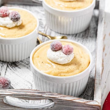 three ramekins filled with pudding in a white wooden tray