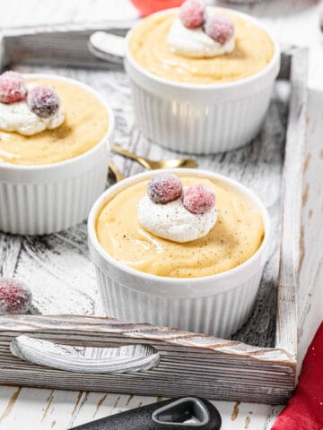 three ramekins filled with pudding in a white wooden tray