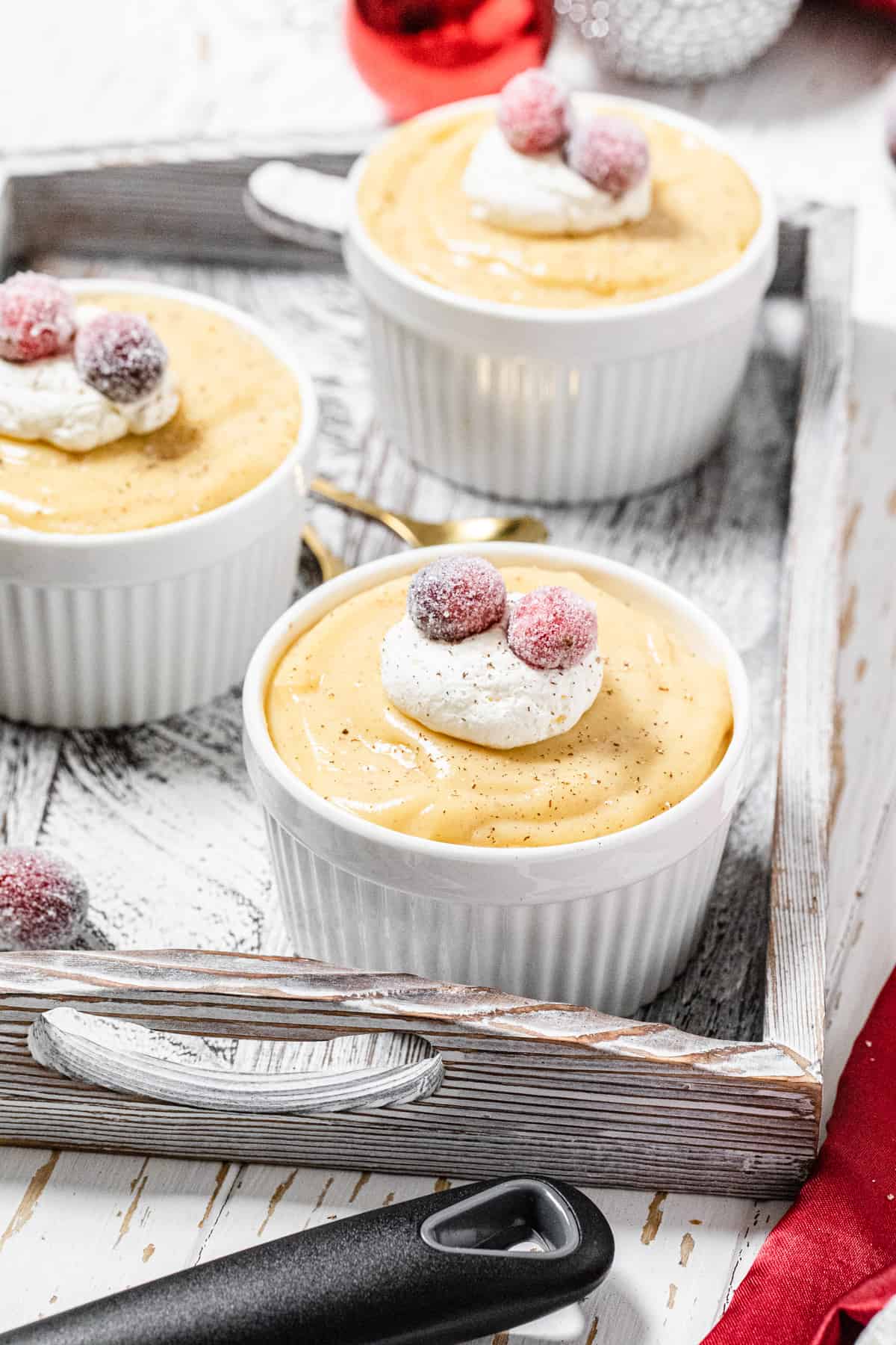 three ramekins filled with pudding in a white wooden tray