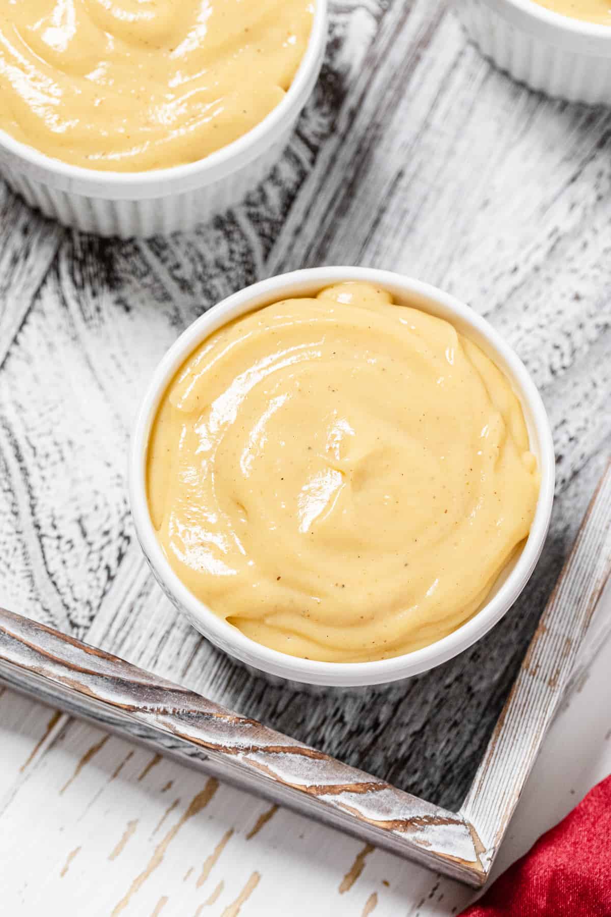 top view close up of plain pudding in a white ramekin in a wooden tray