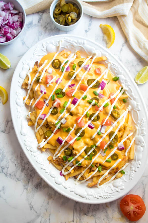 These Loaded Cheese Fries are guaranteed to be a crowd pleaser! Crisp french fries loaded with hot Italian sausage, jalapeños, red onions, green onions, tomatoes, sour cream and a creamy and delicious cheese sauce!