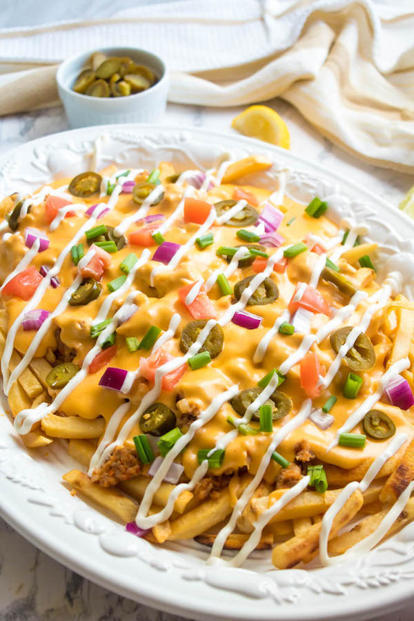 These Loaded Cheese Fries are guaranteed to be a crowd pleaser! Crisp french fries loaded with hot Italian sausage, jalapeños, red onions, green onions, tomatoes, sour cream and a creamy and delicious cheese sauce!