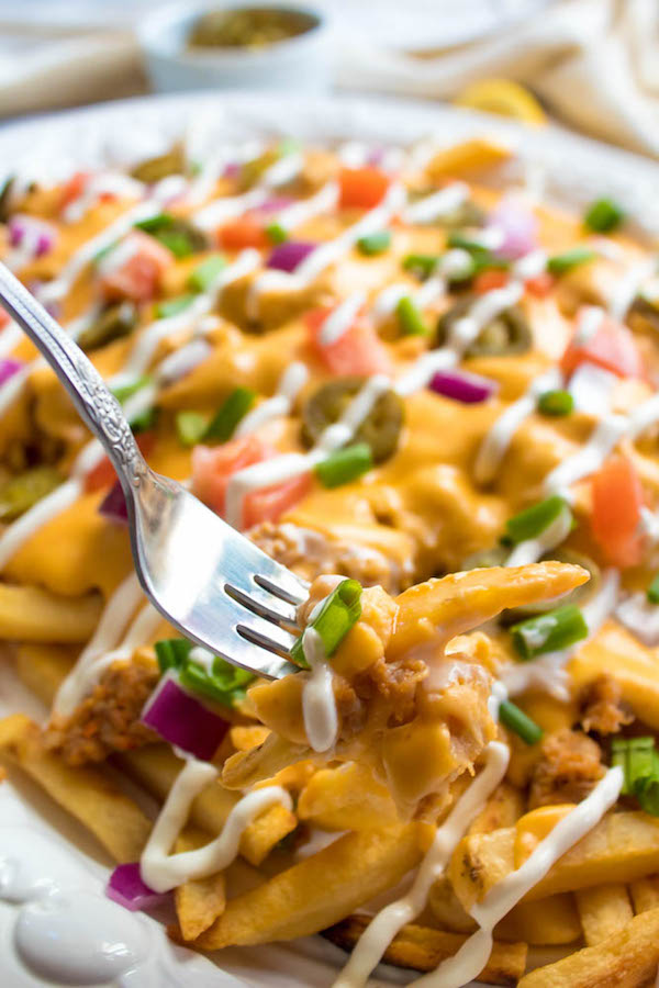 These Loaded Cheese Fries are guaranteed to be a crowd pleaser! Crisp french fries loaded with hot Italian sausage, jalapeños, red onions, green onions, tomatoes, sour cream and a creamy and delicious cheese sauce!