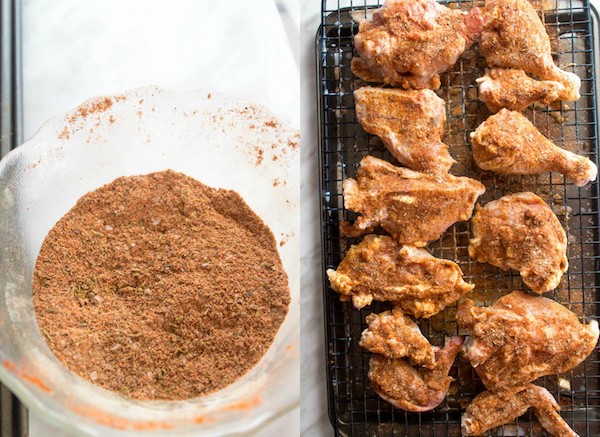 seasoning in a small bowl and seasoning on raw chicken pieces on a cooling rack and baking sheet